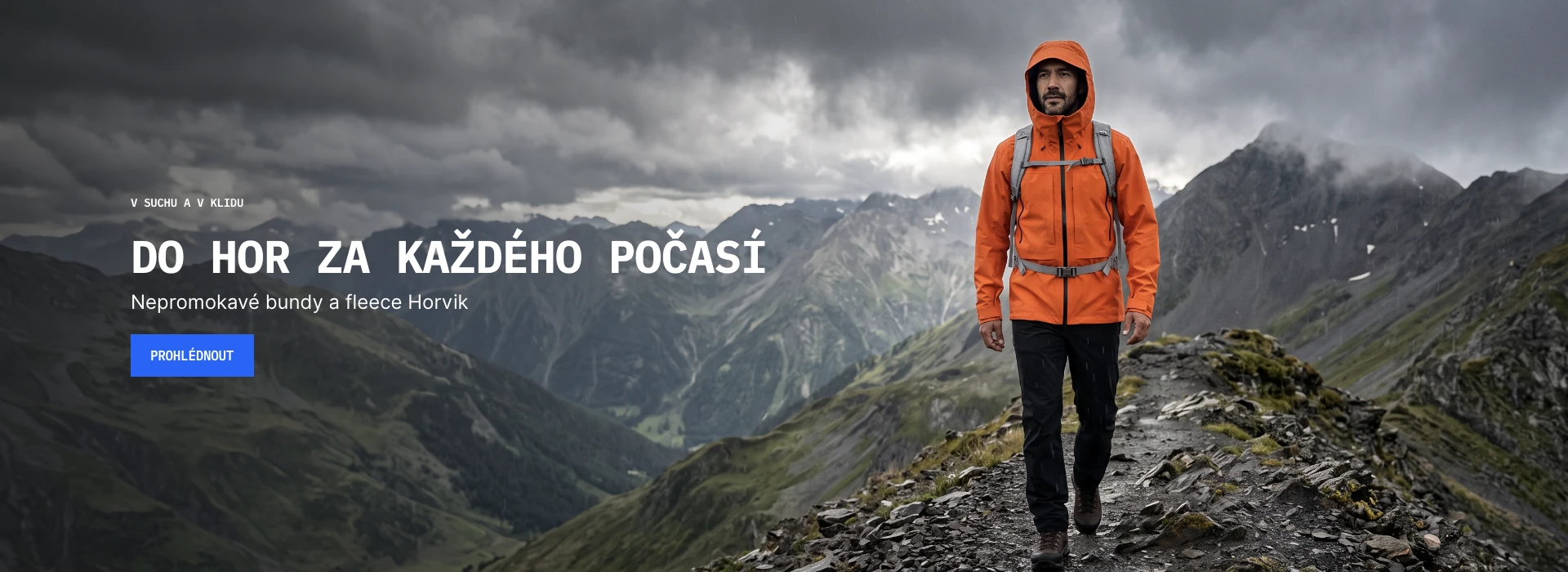 Turista v oranžové nepromokavé bundě Horvik Shell na horském hřebeni
